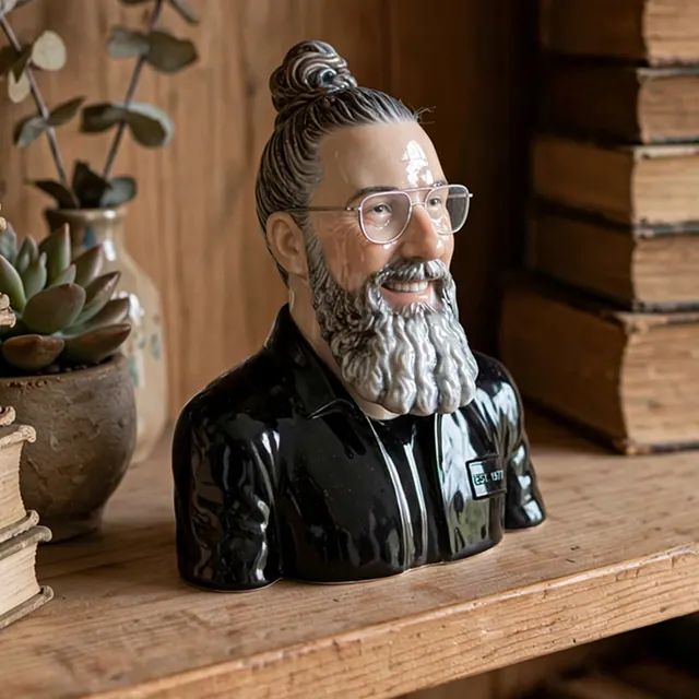 Tiny glossy porcelain bust of a person on a wooden bookshelf